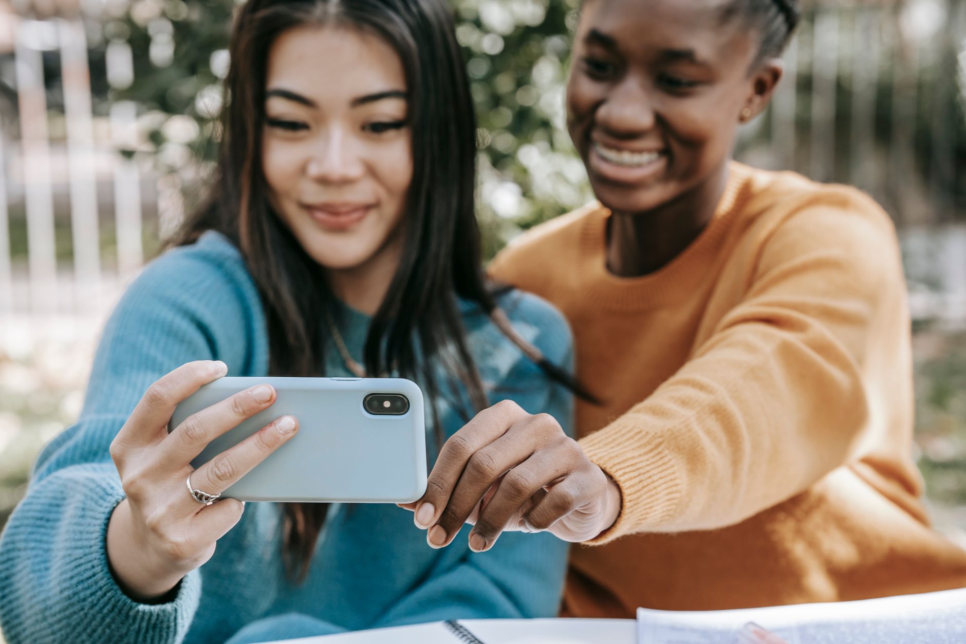 Amis multiraciaux heureux prenant un selfie avec un téléphone portable à table dans la rue en journée